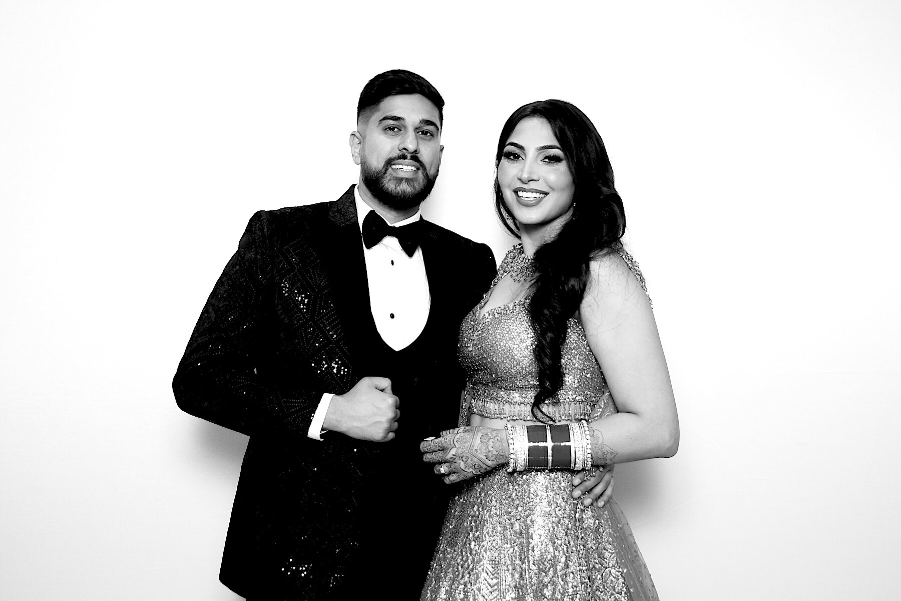 Bride and groom in formal wedding attire smiling in a black-and-white portrait
