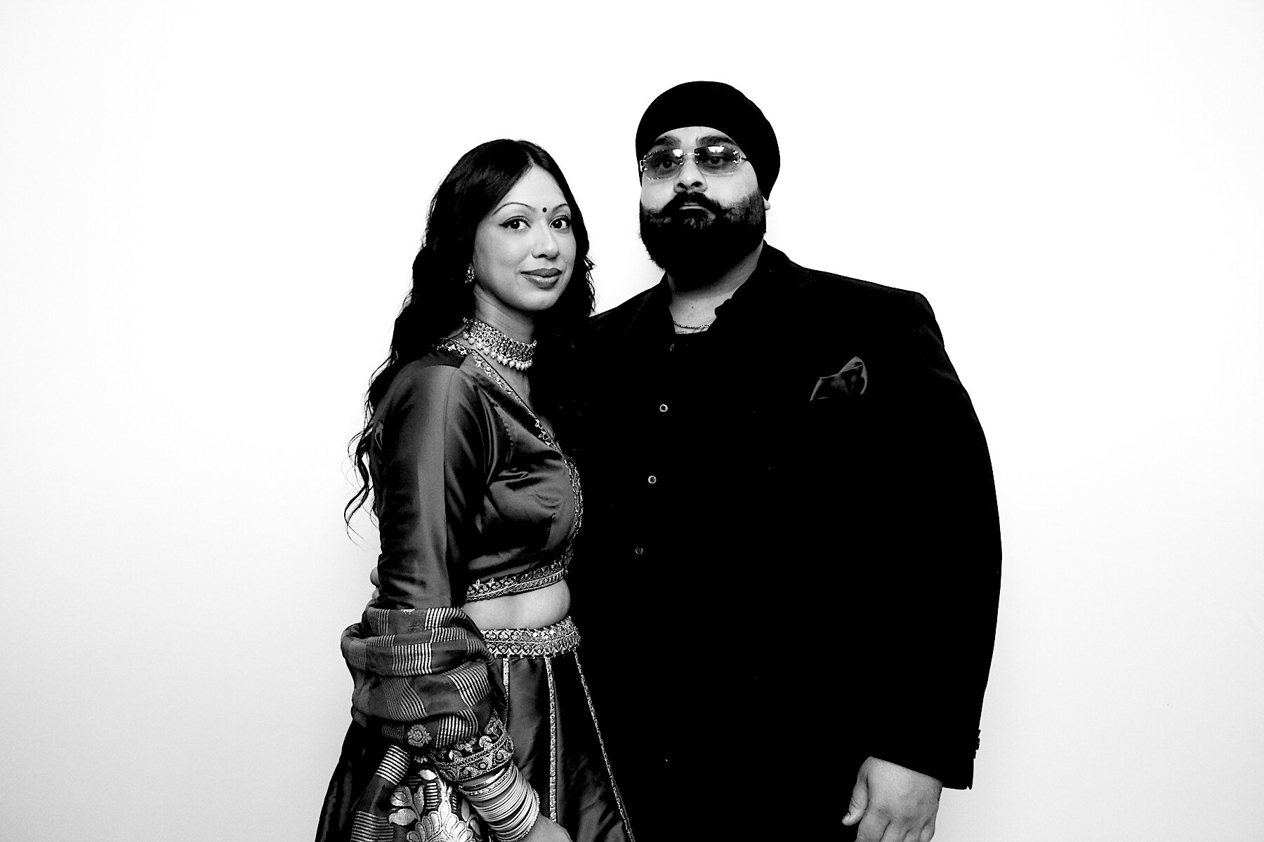 Couple in festive attire posing in black and white