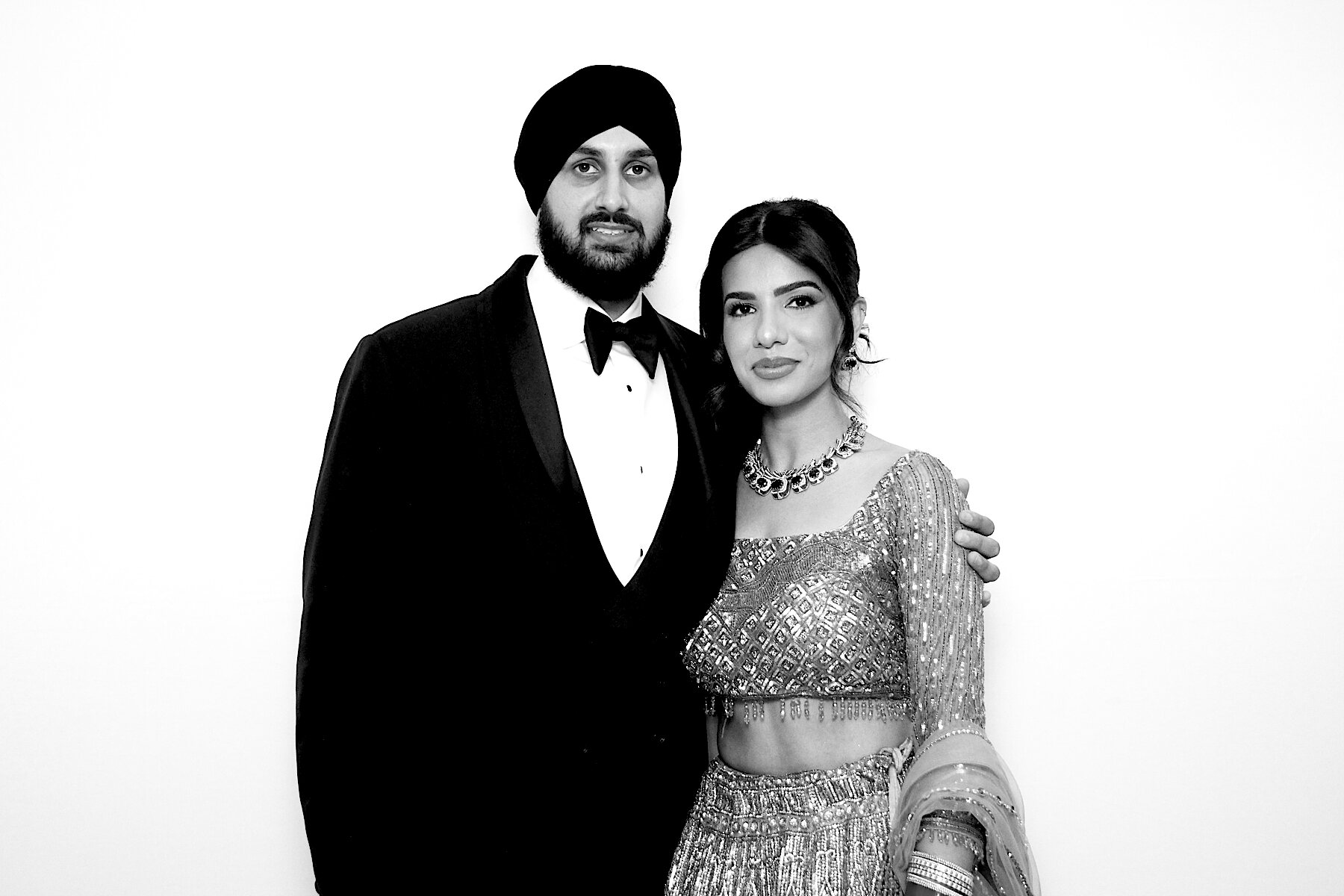 Couple in a tuxedo and embellished lehenga in a black-and-white portrait