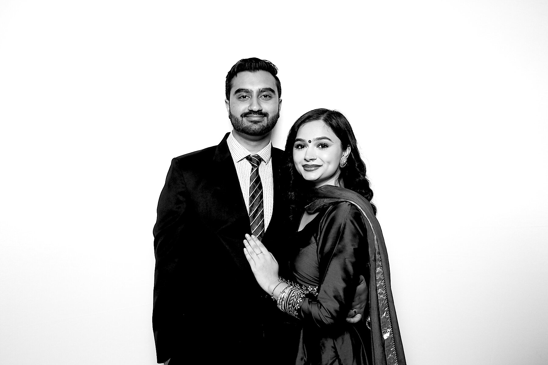 Couple in a suit and traditional outfit posing in black and white