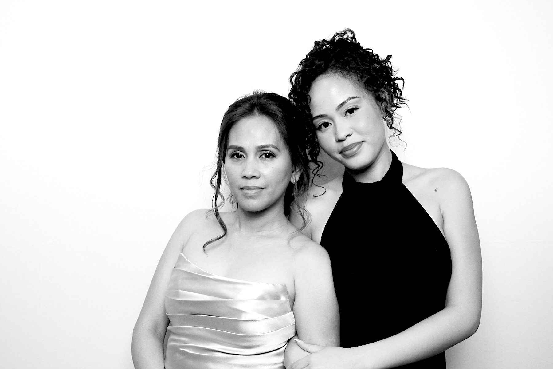 Two guests in evening dresses posing together in black and white